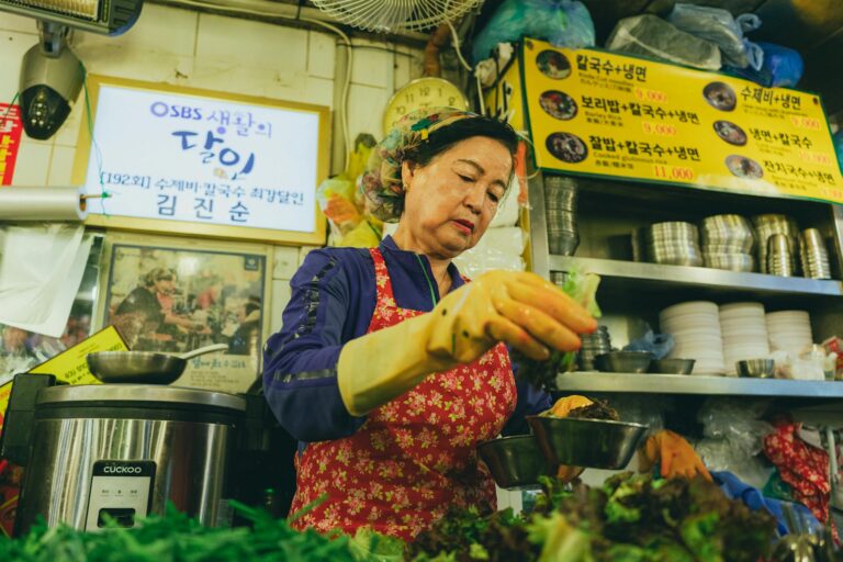 A woman preparing food in a traditional Korean market in Seoul, showcasing vibrant culinary culture.