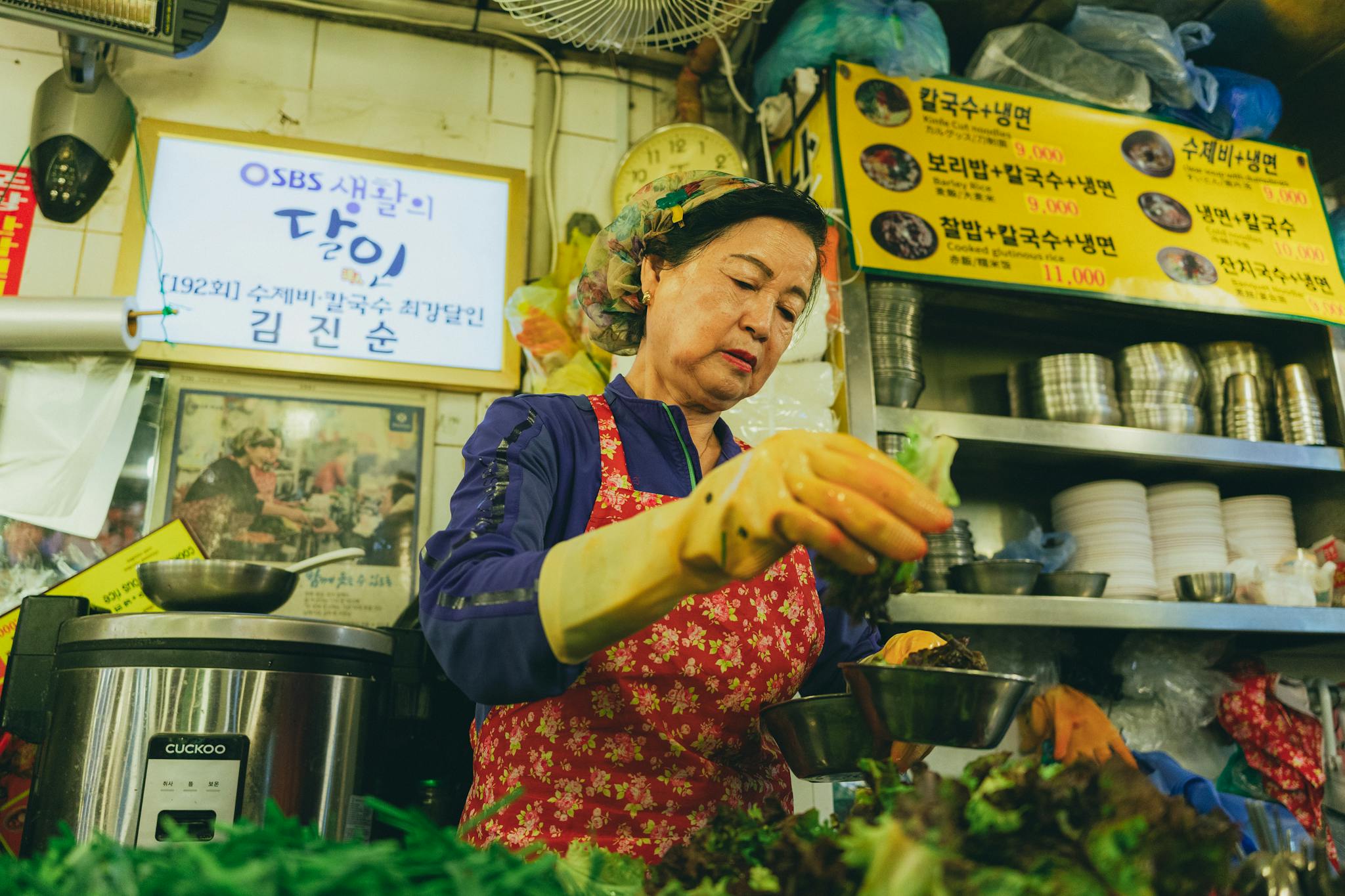 A woman preparing food in a traditional Korean market in Seoul, showcasing vibrant culinary culture.