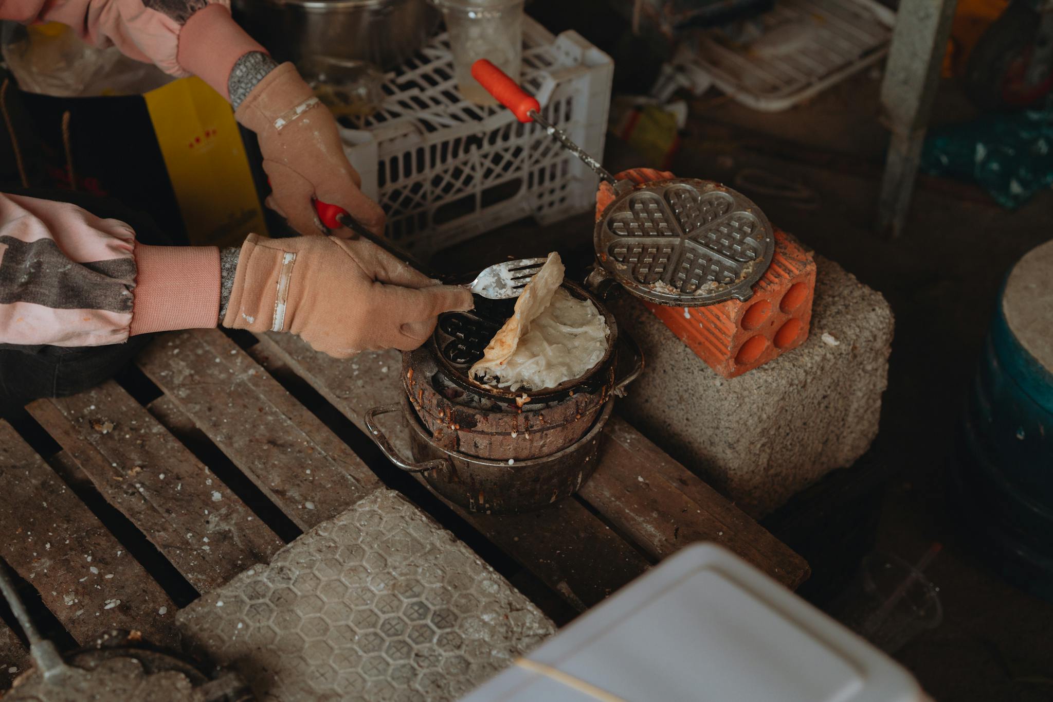 Close-up of an artisan cooking waffles on a rustic, traditional setup in Vietnam.